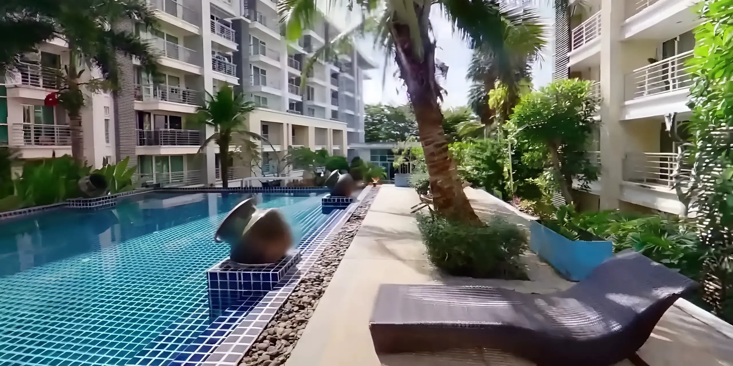 Large outdoor swimming pool lined with palm trees and the condominium towers behind